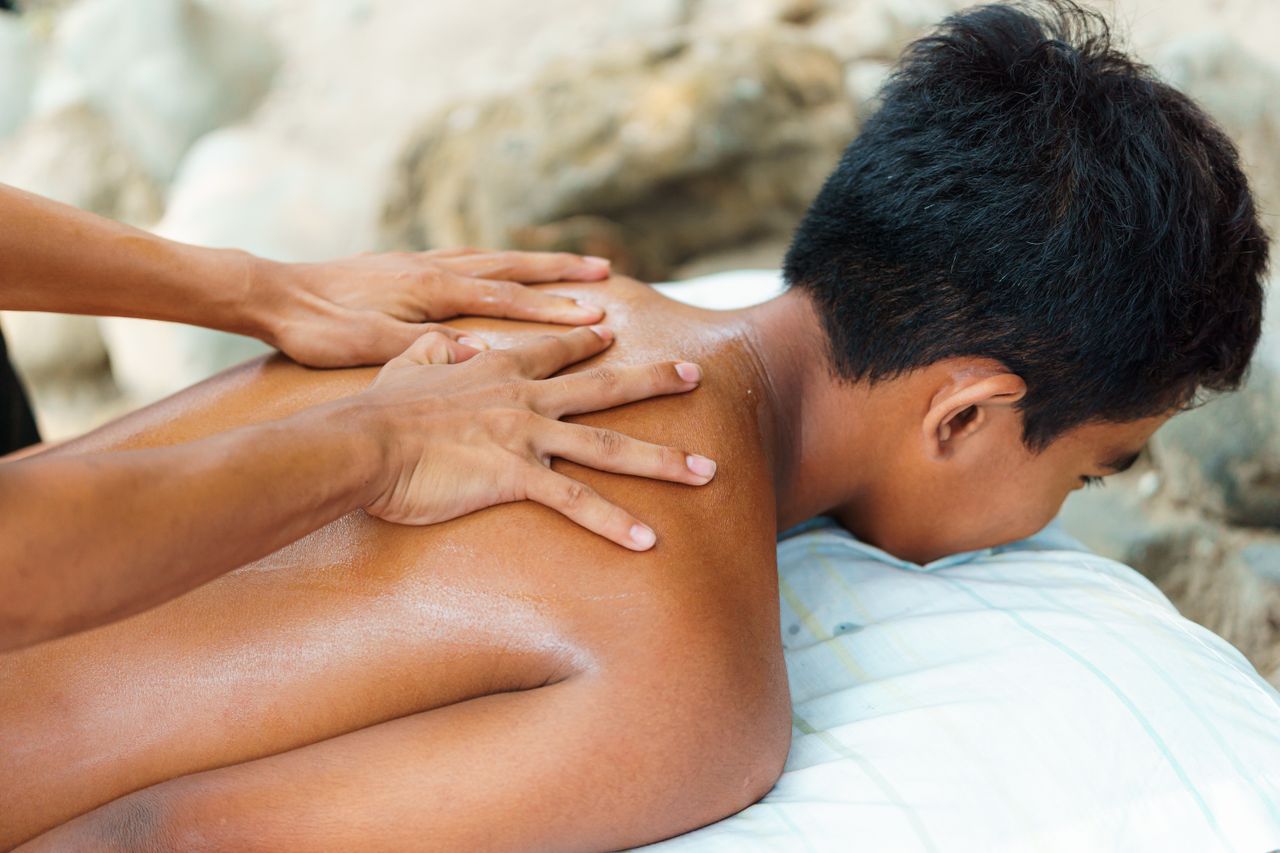 Home Person receiving a back massage outdoors, emphasizing relaxation and wellness.