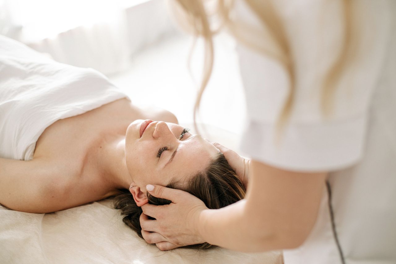 A woman receiving a calming head massage at a spa, promoting relaxation and wellness.